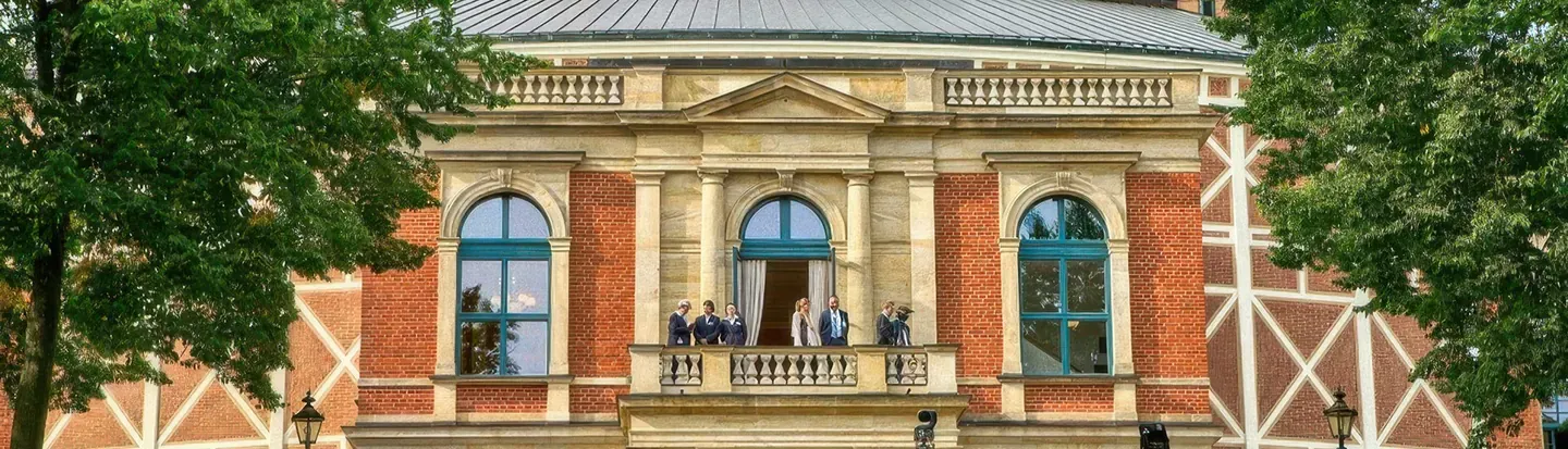 Fachada de ladrillo y piedra de la sede del Festival de Bayreuth entre árboles
